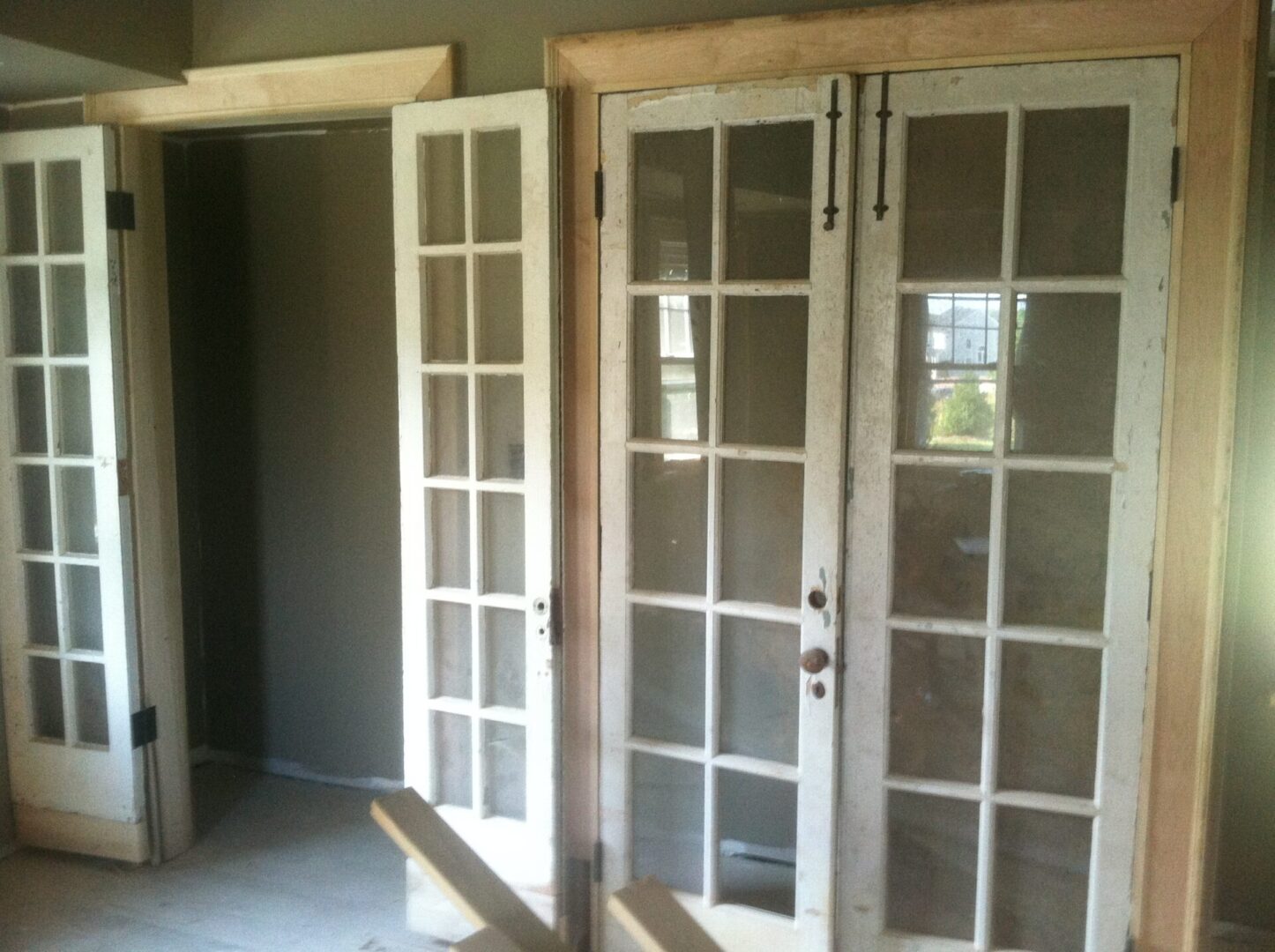 Two white wood double doors with window paneling on them