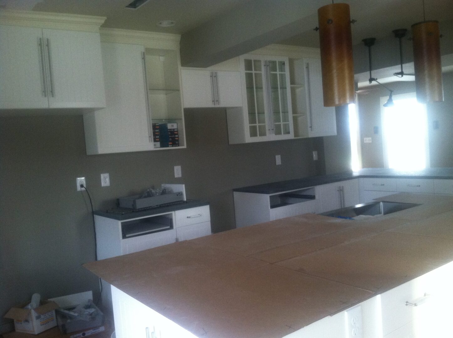 Grey-walled kitchen space with white cabinetry being constructed