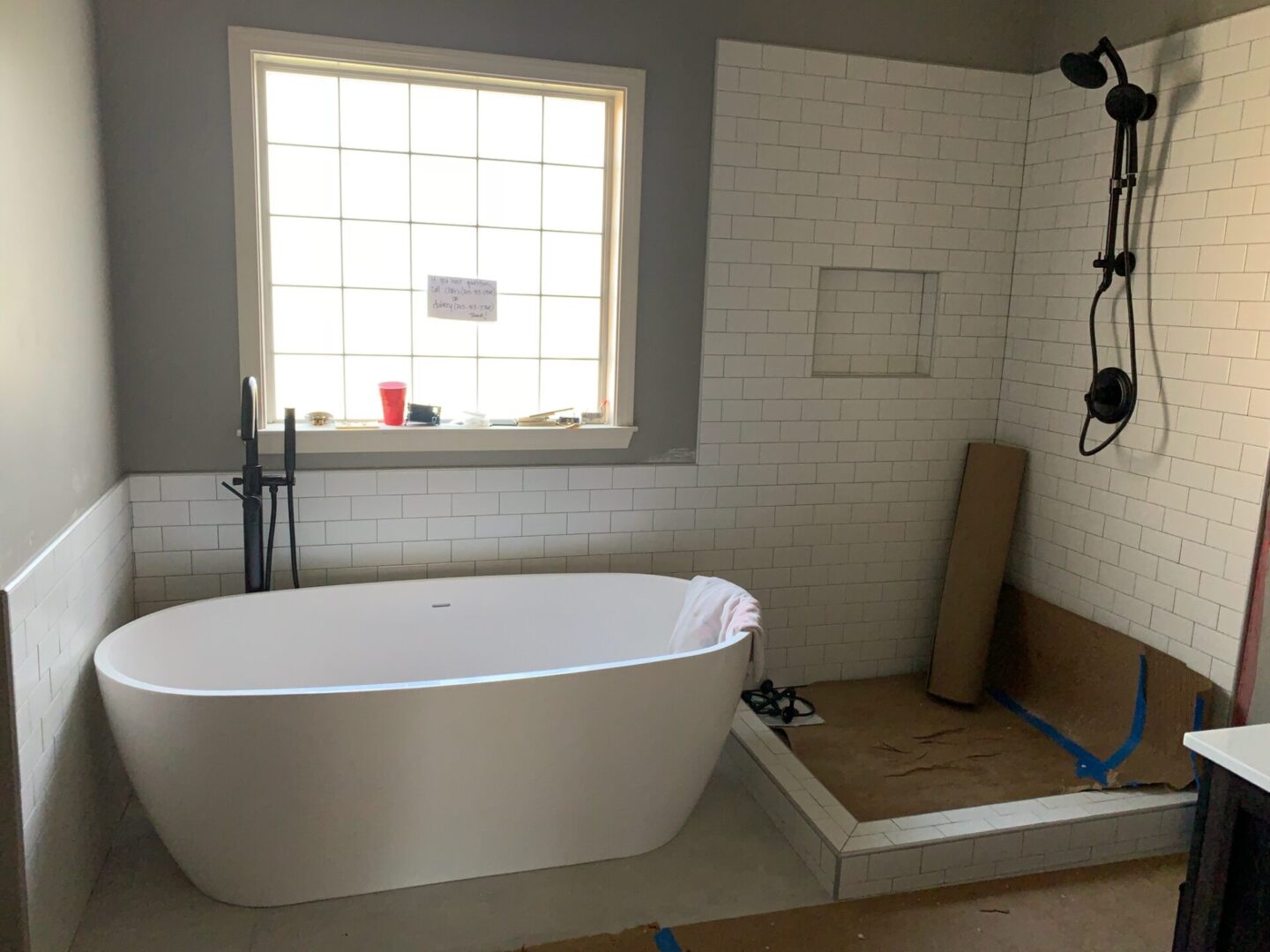 Grey-walled bathroom with half-wall tiling for a bathtub space and full-wall tiling for a shower space