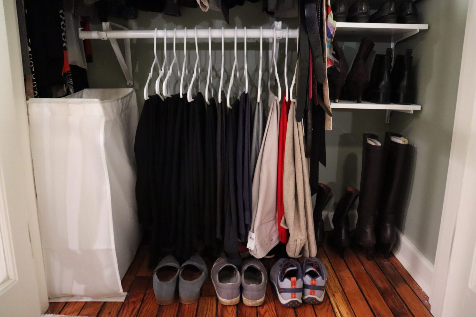 One level of hanged clothes next to a shoe dresser in a closet