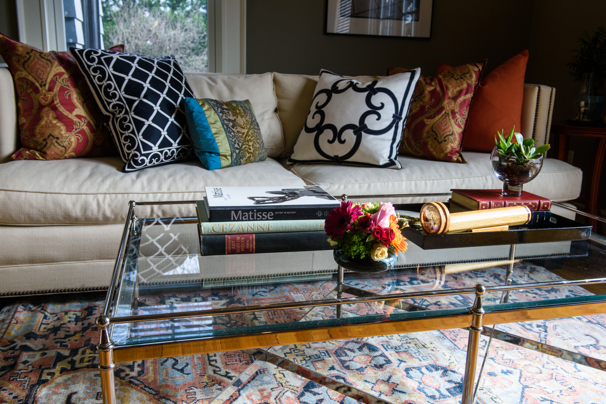 White couch with assorted throw pillows behind a glass coffee table